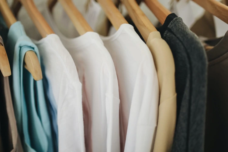 A close up of several shirts hanging on clothes racks.