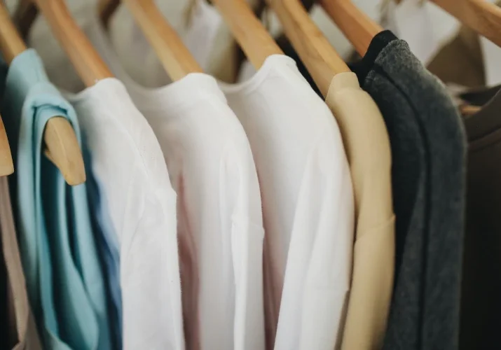 A close up of several shirts hanging on clothes racks.